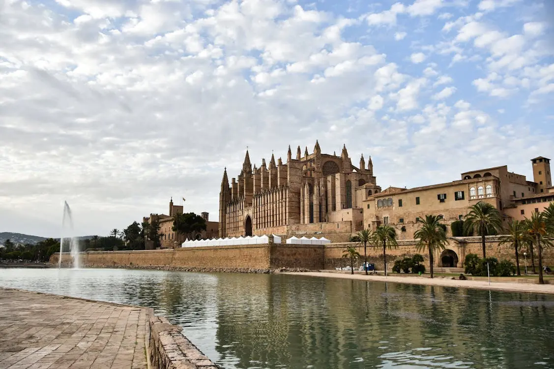 Vista de la Catedral de Mallorca junto al agua bajo un cielo con nubes