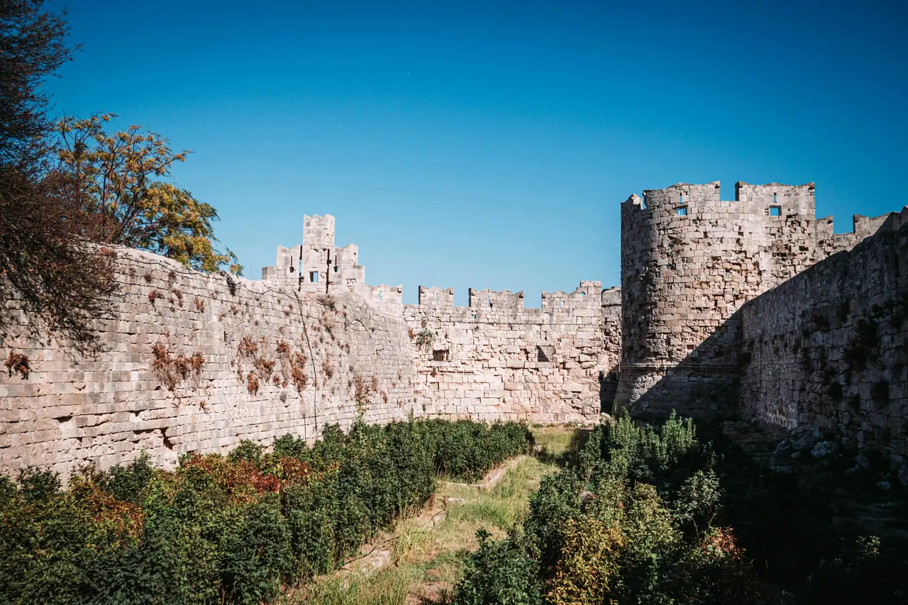 Murallas medievales y torre de la ciudad de Rodas bajo un cielo azul