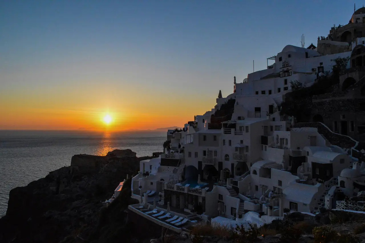 Casas blancas con cúpulas azules de Santorini al atardecer sobre la caldera