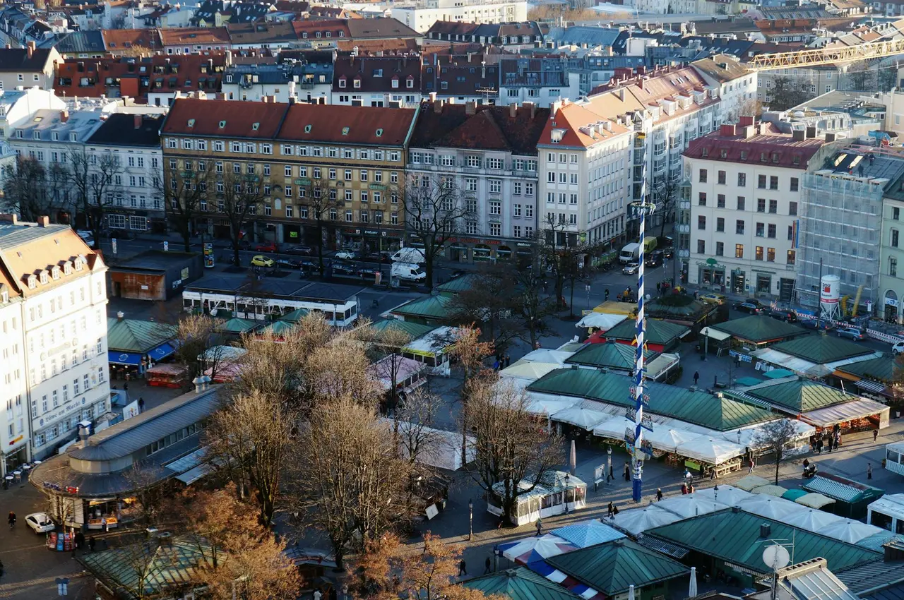 El Viktualienmarkt de Munich con puestos de comida y la torre de la iglesia al fondo