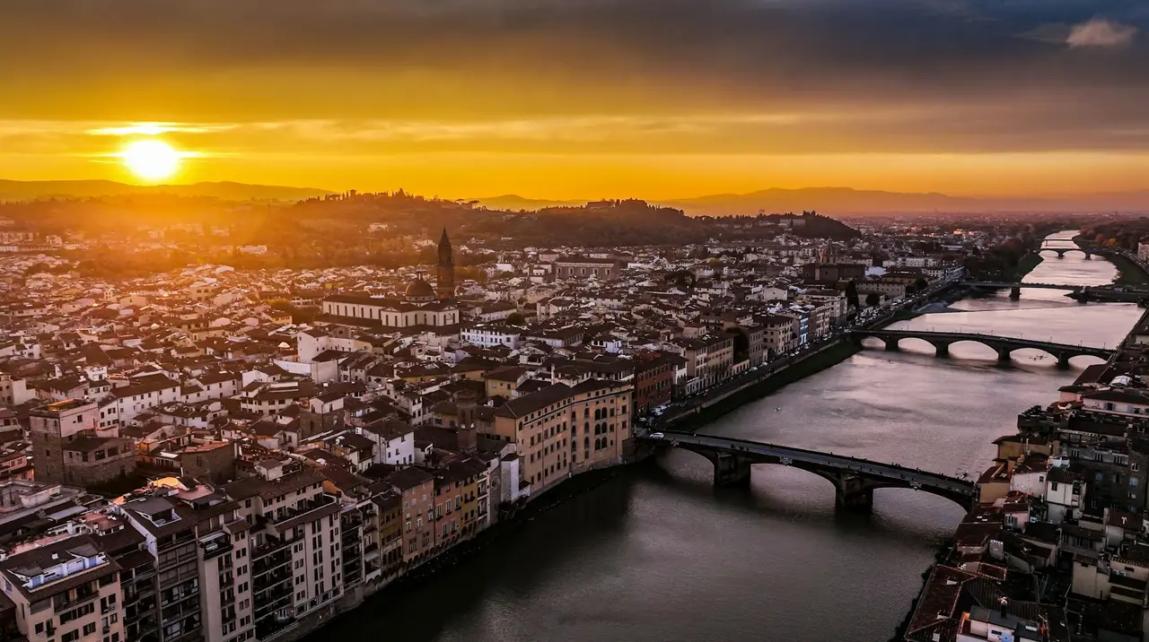 Vista aérea de Florencia al atardecer con el río Arno y el Ponte Vecchio iluminados por la luz dorada