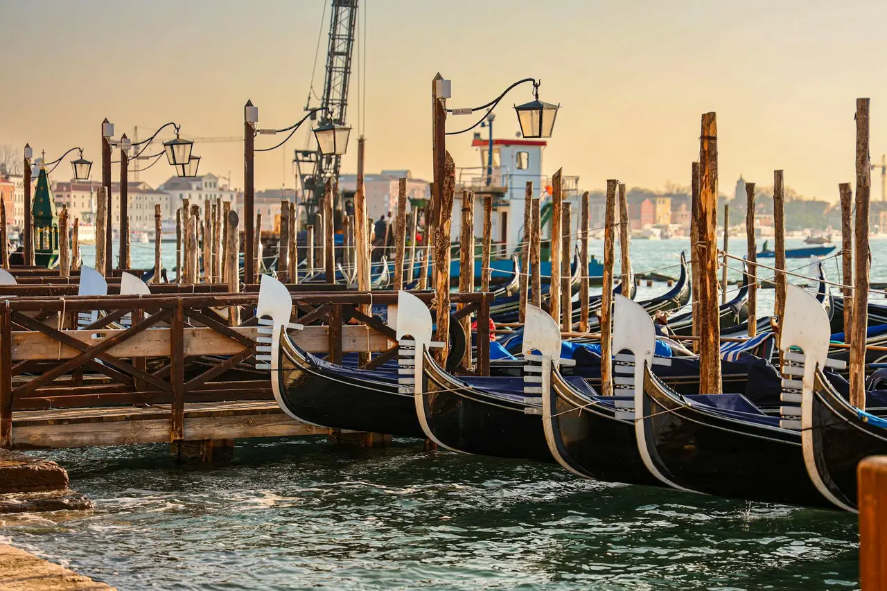 Góndolas amarradas al amanecer en un canal de Venecia, sin turistas, reflejando la calma de la ciudad temprana