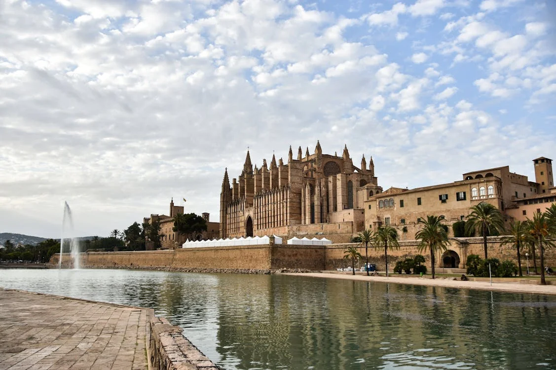 Vista de la Catedral de Mallorca junto al agua bajo un cielo con nubes