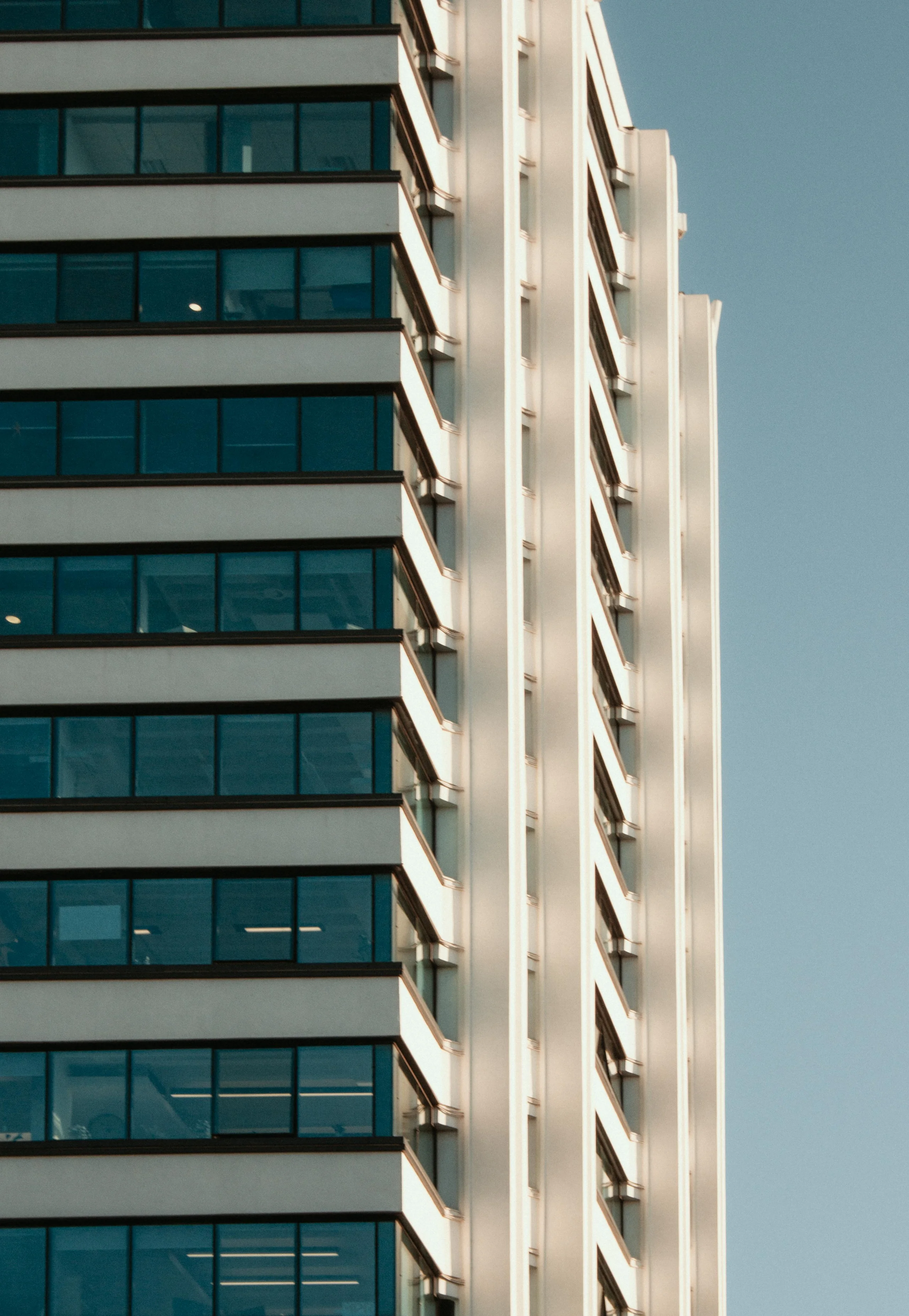 Rascacielos moderno de cristal en Manchester reflejando el cielo azul, mostrando la arquitectura contemporanea de la ciudad